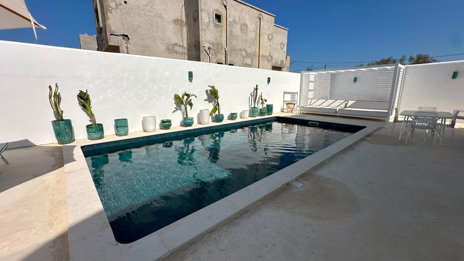 La piscine de Casa Noah sous un ciel bleu, le salon d'extérieur au fond