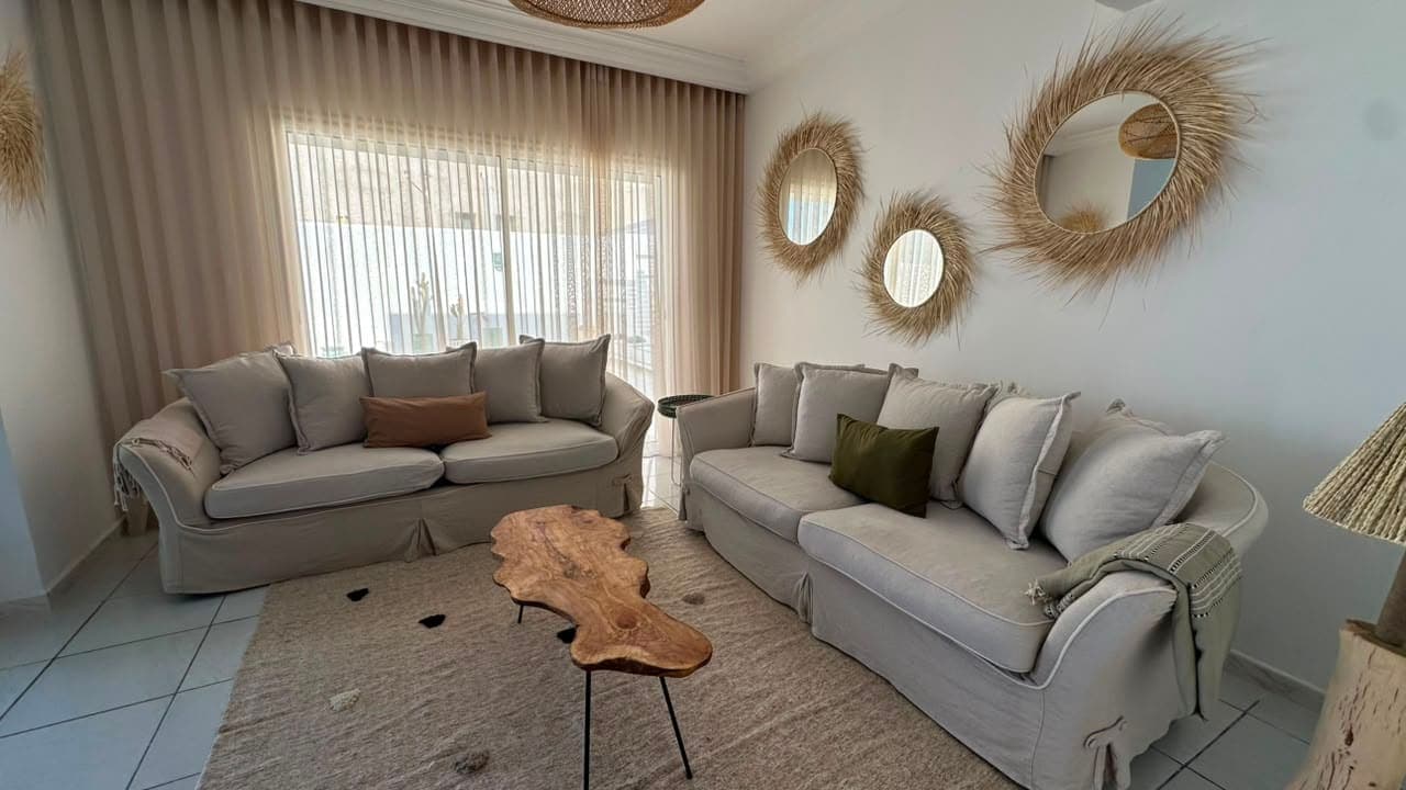 Le salon : deux canapés en lin, table basse en bois, miroirs en fibres tressées